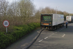 A lay-by, with a sign saying Long Loads, with HGVs parked in it.