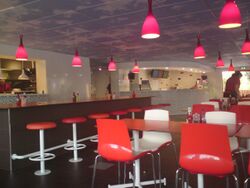 Inside a restaurant with shiny red seats and blue sky painted on the ceiling.