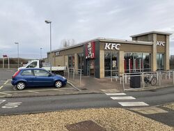 A KFC restaurant with cars parked outside it.