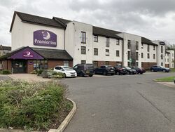 Three-storey hotel building with a Premier Inn sign and cars parked outside it.
