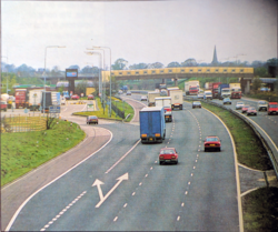 An old photo of the M6 motorway, with its steel central barrier and red hard shoulder.