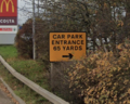 A road sign saying 'car park entrance 65 yards'.