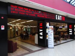 Signs saying Eat In, across a restaurant entrance.