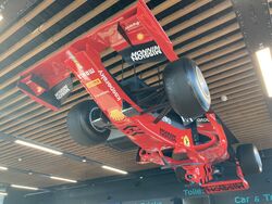 A red Formula 1 car, attached upside down to a wooden roof.